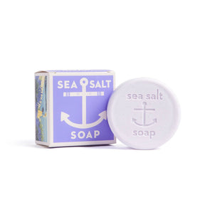 A round Sea Salt Lavender Swedish Dream Bar Soap, triple milled and natural, features an anchor emboss and sits beside its purple and white box. This 4 oz bar blends sea salt benefits with soothing lavender for gentle skincare.