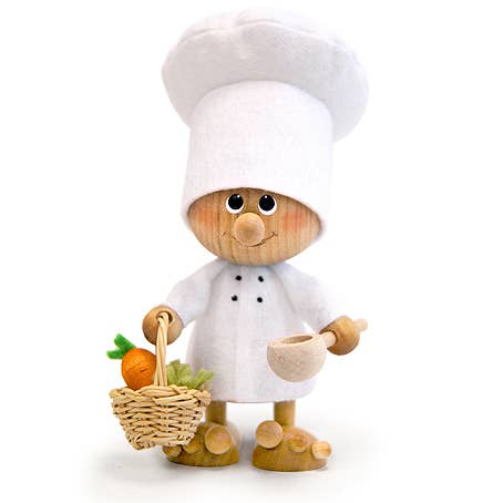 The Figurine: Chef with Basket, a handcrafted piece reflecting Scandinavian decor, wears a white hat and coat while artistically balancing a small vegetable basket in one hand and holding a ladle in the other.