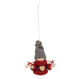 Ornament of a small gnome figure with a gray knit hat, red sweater, and heart-shaped button on the front, suspended by a string.
