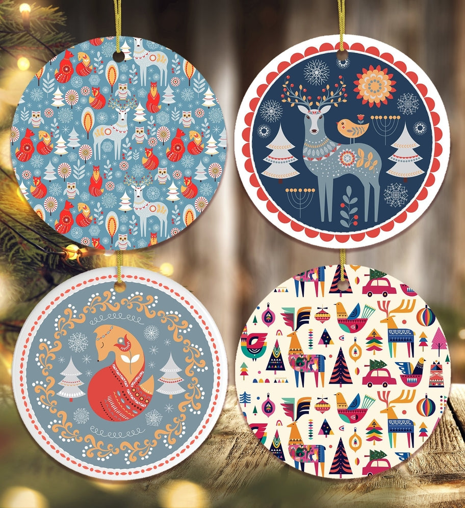Four round "Ornament: Scandinavian Deer Christmas" ceramics feature whimsical winter animal and tree designs in red, blue, white, and gold tones, hanging with evergreens for a charming holiday display.