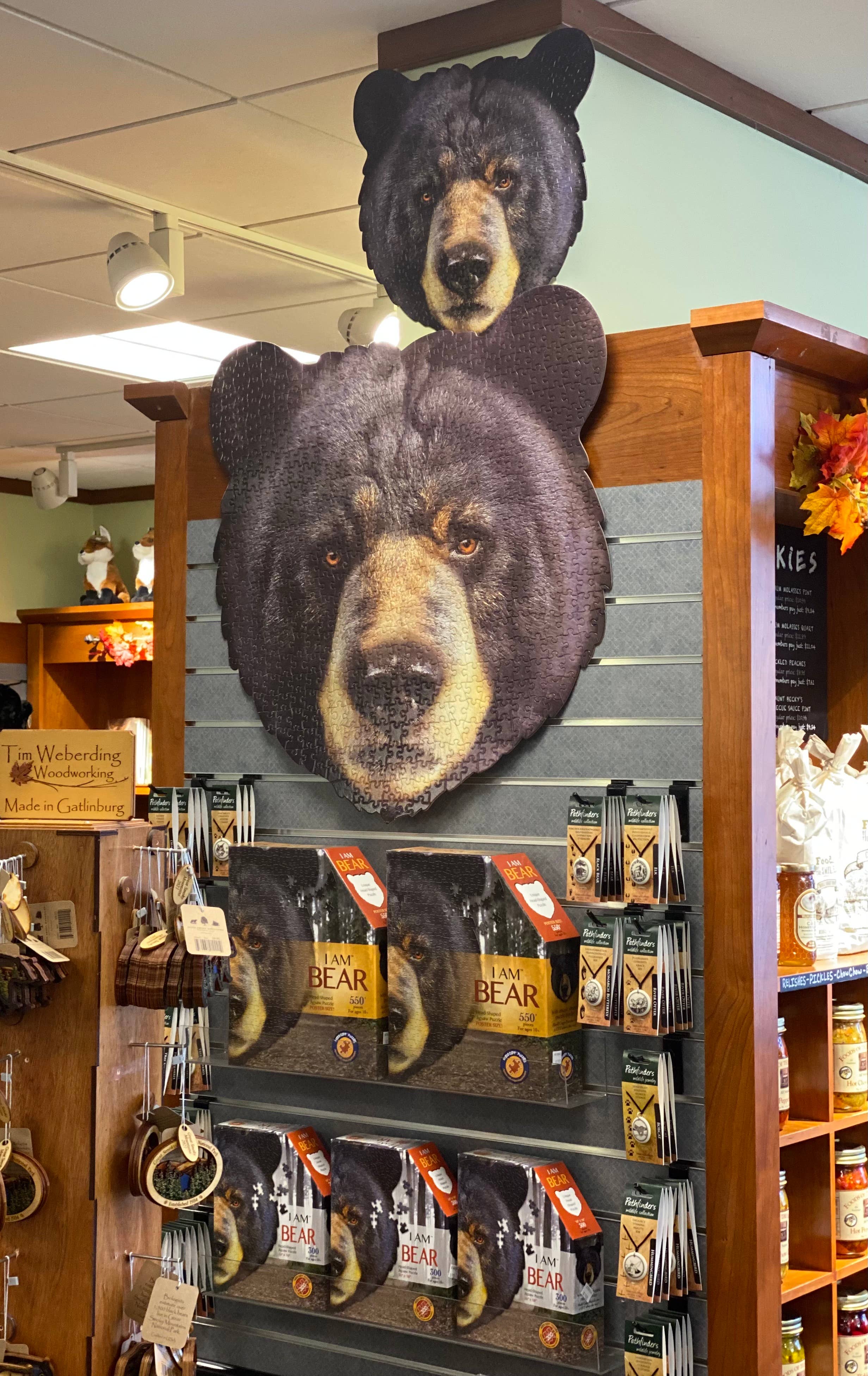 The store display features bear-themed decor including "I Am Bear" books and distinctive bear head cutouts mounted on a wooden shelf. Explore the educational "Puzzle: I Am Bear - Shaped Jigsaw (300 Pieces)" for fun facts about these majestic creatures.