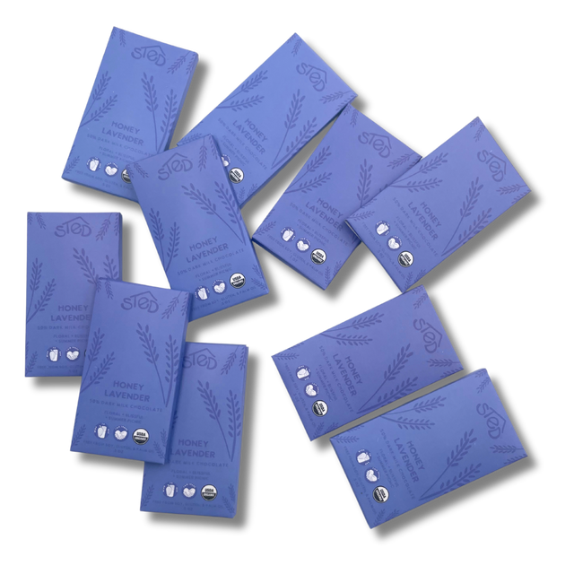 Ten purple chocolate bars with lavender illustrations and organic milk chocolate certification logos scattered on a white background.