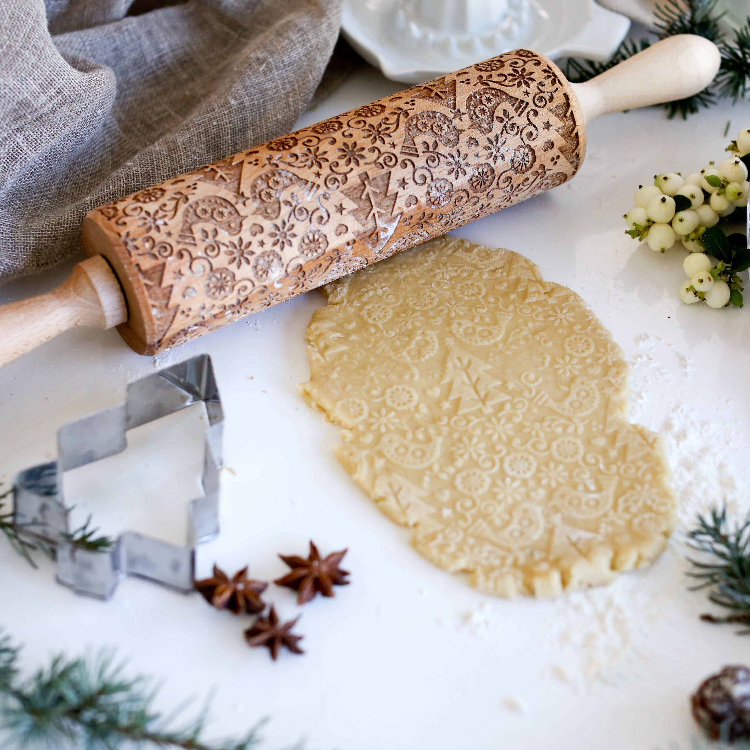 Decorative handmade Scandinavian 4 - Birds and Trees rolling pin with embossing patterns on dough, includes a star-shaped cookie cutter and seasonal decorations.