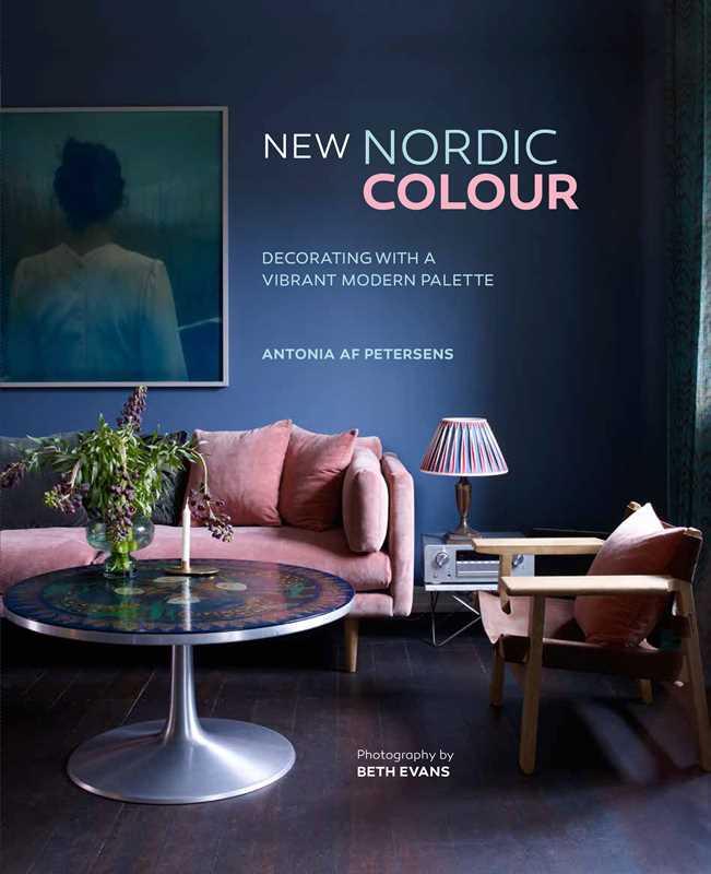 A modern living room with a pink sofa, round coffee table, and armchair exudes Scandinavian style, featuring the Book: New Nordic Colour by Antonia af Petersens on display.