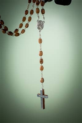 A Rosary: Olive Wood Rosary with Crucifix and water from Jordan is set against a light green background, capturing the sacred essence of the Holy Land.