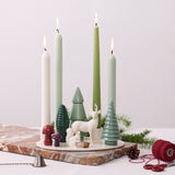 Nordic advent candle holder with four lit taper candles on a marble base, decorated with miniature ceramic deer, a squirrel, trees, and mushrooms.
