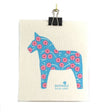 The eco-friendly Dish Cloth: Dalahäst Turquoise Dala Horse by Anneko Design Sweden features a turquoise Dala horse and pink flowers, clipped at the top with a black binder clip and "anneko design sweden" printed below the illustration.