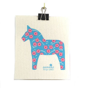 The eco-friendly Dish Cloth: Dalahäst Turquoise Dala Horse by Anneko Design Sweden features a turquoise Dala horse and pink flowers, clipped at the top with a black binder clip and "anneko design sweden" printed below the illustration.