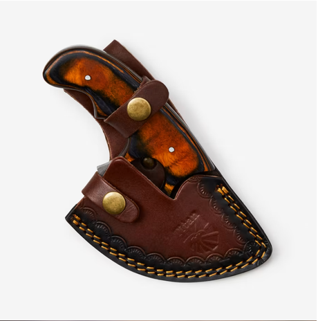The Knife: Alaskan Ulu Style Blade features a polished wood handle and high carbon Damascus steel blade, housed in a brown leather sheath with brass snaps and decorative stitching.