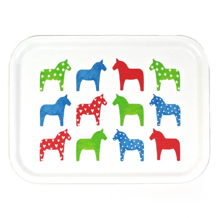 The Dalahast Decorative Tray 27x20 cm - Dalahäst, designed by Anneko Design Sweden, is a delightful birch veneer breakfast tray showcasing a grid of colorful horses in red, blue, and green. Enjoy the unique patterns—hearts, spots, or stars—that embellish each vibrant color.