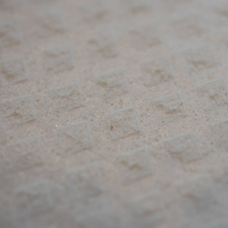 Close-up of a white Swedish Dishcloth with a grid pattern of raised squares on the textured surface.