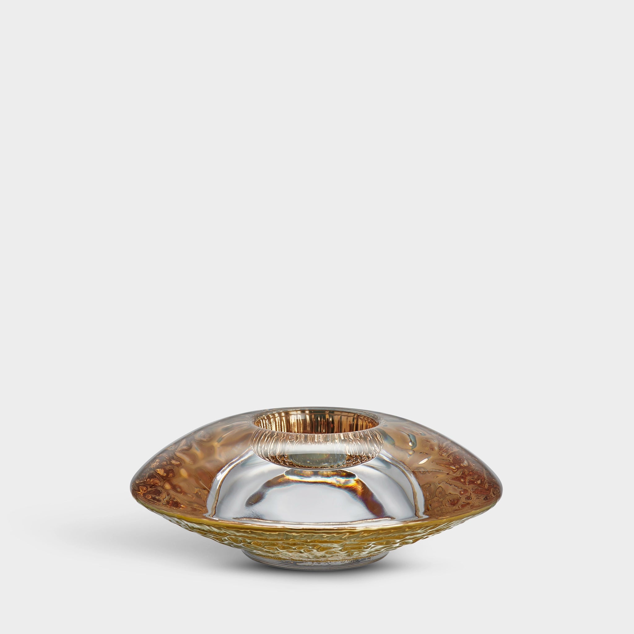 The Orrefors Discus Gold Votive Candle Holder features a metallic bowl with a reflective silver and gold finish, an elegant rounded design, and a central opening evocative of the brands signature style.