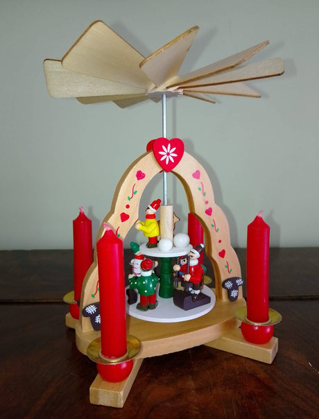 Four red Christmas Pyramid Candles (Pyramiden-Kerzen, 14 x 70mm) from a box of 50 light up a wooden Christmas candle carousel with spinning fan top and festive figurines, all beautifully crafted and made in Germany.