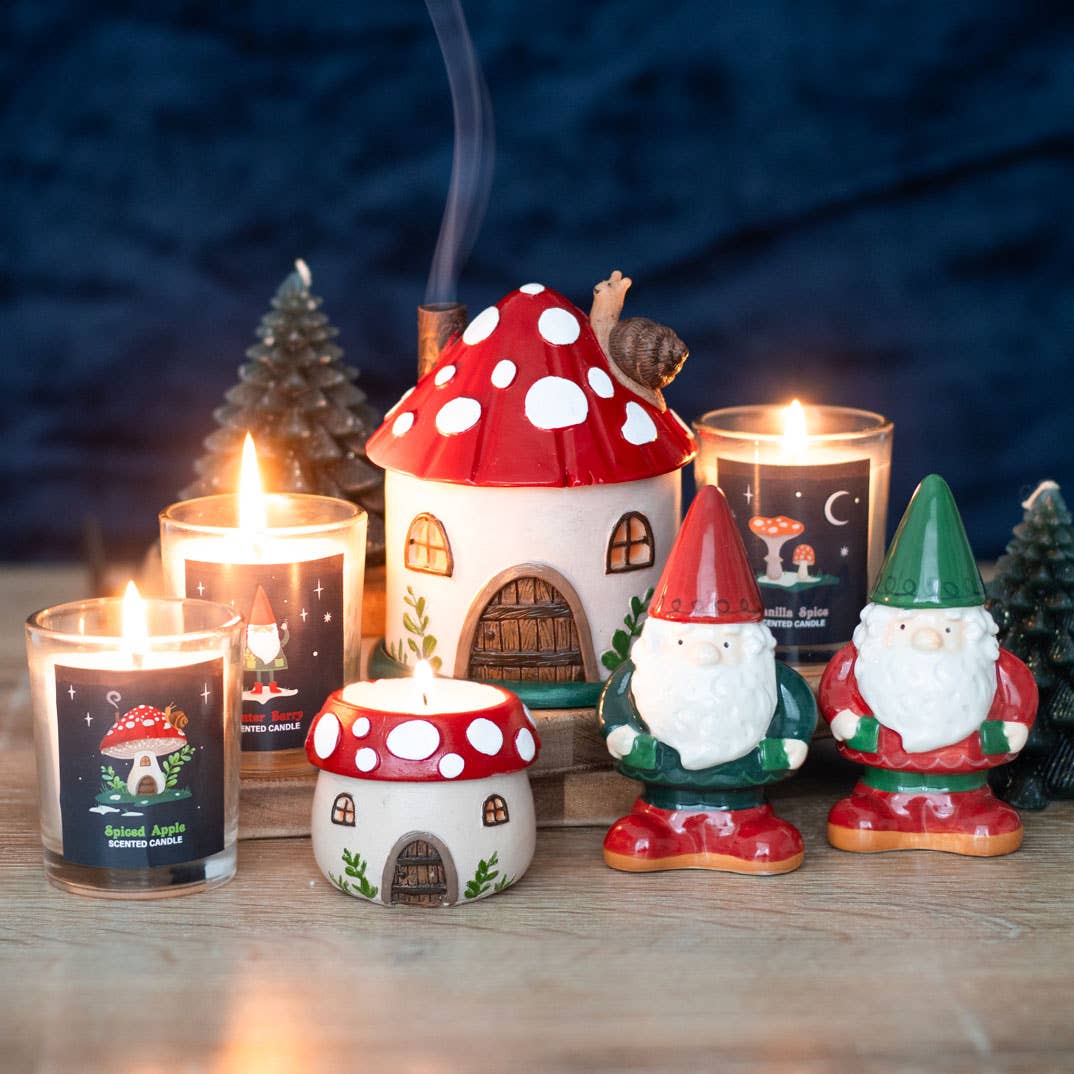 A variety of decorative candles and figurines, featuring mushroom-shaped houses and gnomes, along with the delightful Shakers: Gnome Salt & Pepper Shakers, are arranged on a wooden surface.