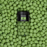 A jar of Lakrids: Sour Strawberry Danish Gourmet Licorice Limited Edition Lakrids by Bulow 4.41 oz is surrounded by numerous green licorice balls of the same variety.