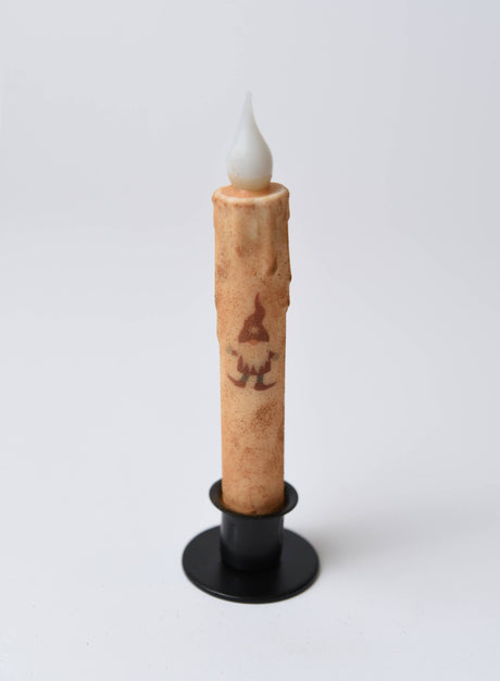 The Candle: Christmas Gnome LED Timer Taper Candle: Cinnamon Dusted features a faux flame, cinnamon-dusted beige finish, gnome illustration, and battery-powered timer—perfect festive decor for the season.