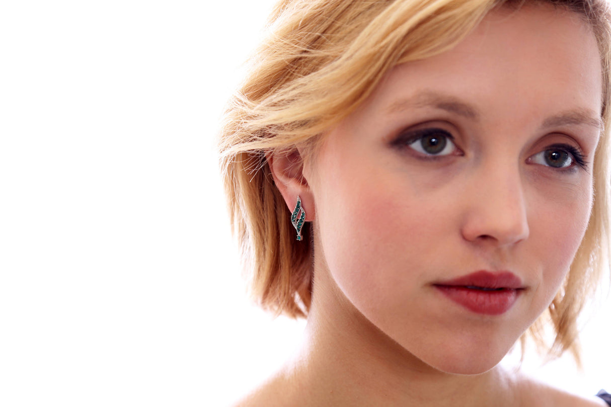 A woman with short blonde hair and light makeup is shown in close-up, wearing May Emerald Beautiful Spiral Swarovski® Crystals Silver Earrings, against a bright white background.
