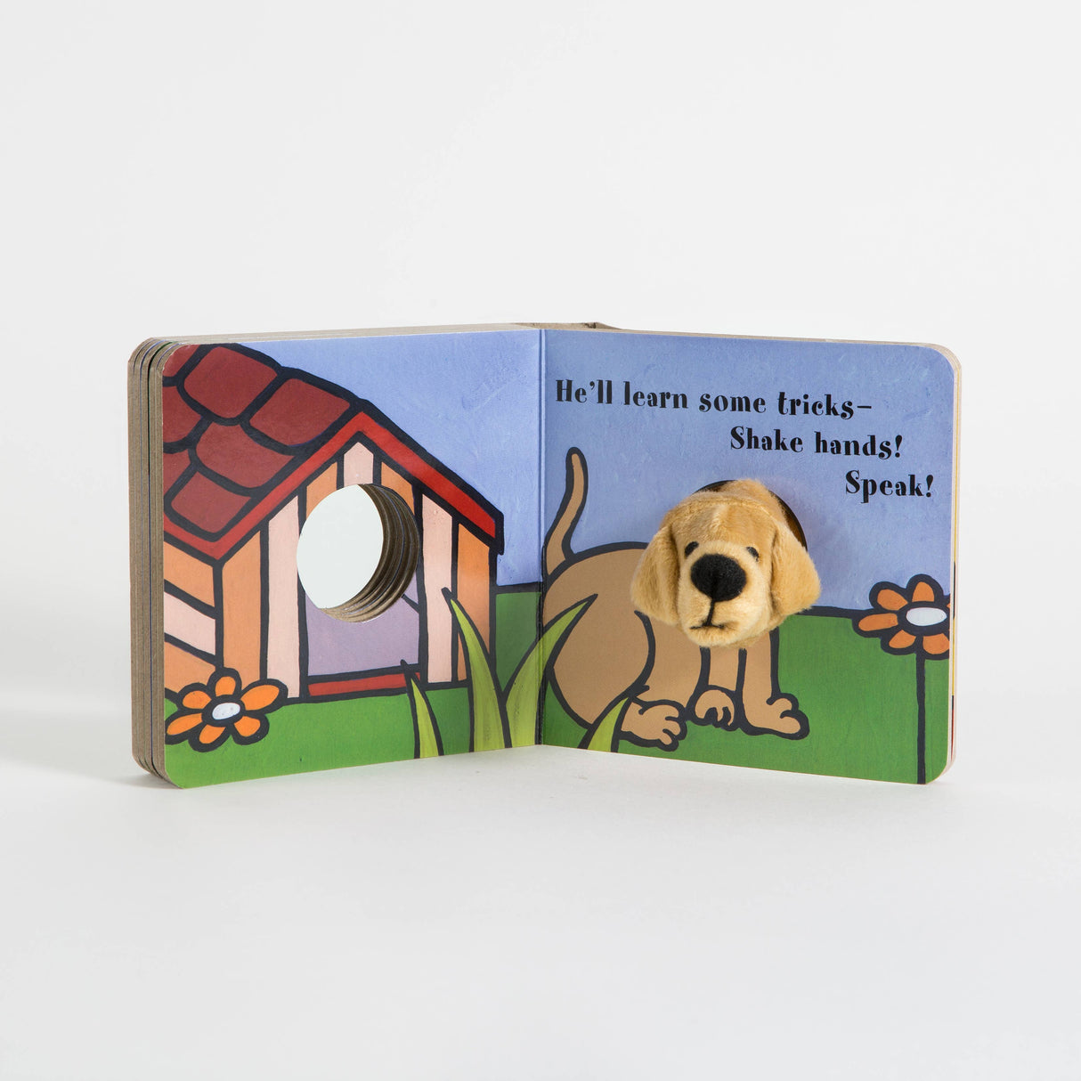 Open Book: Little Puppy Finger Puppet Book to discover a colorful dog and doghouse. The dog's soft puppet head pokes through the page. Text says, "He'll learn some tricks—Shake hands! Speak!" Perfect for interactive baby book fun.
