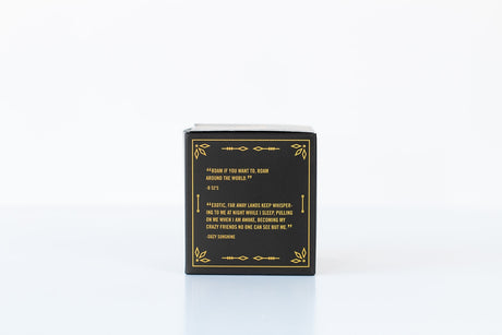 A small black box with gold accents and text on one side, featuring a Soap: Sandalwood & Vanilla Bath Bomb, set against a plain white background.