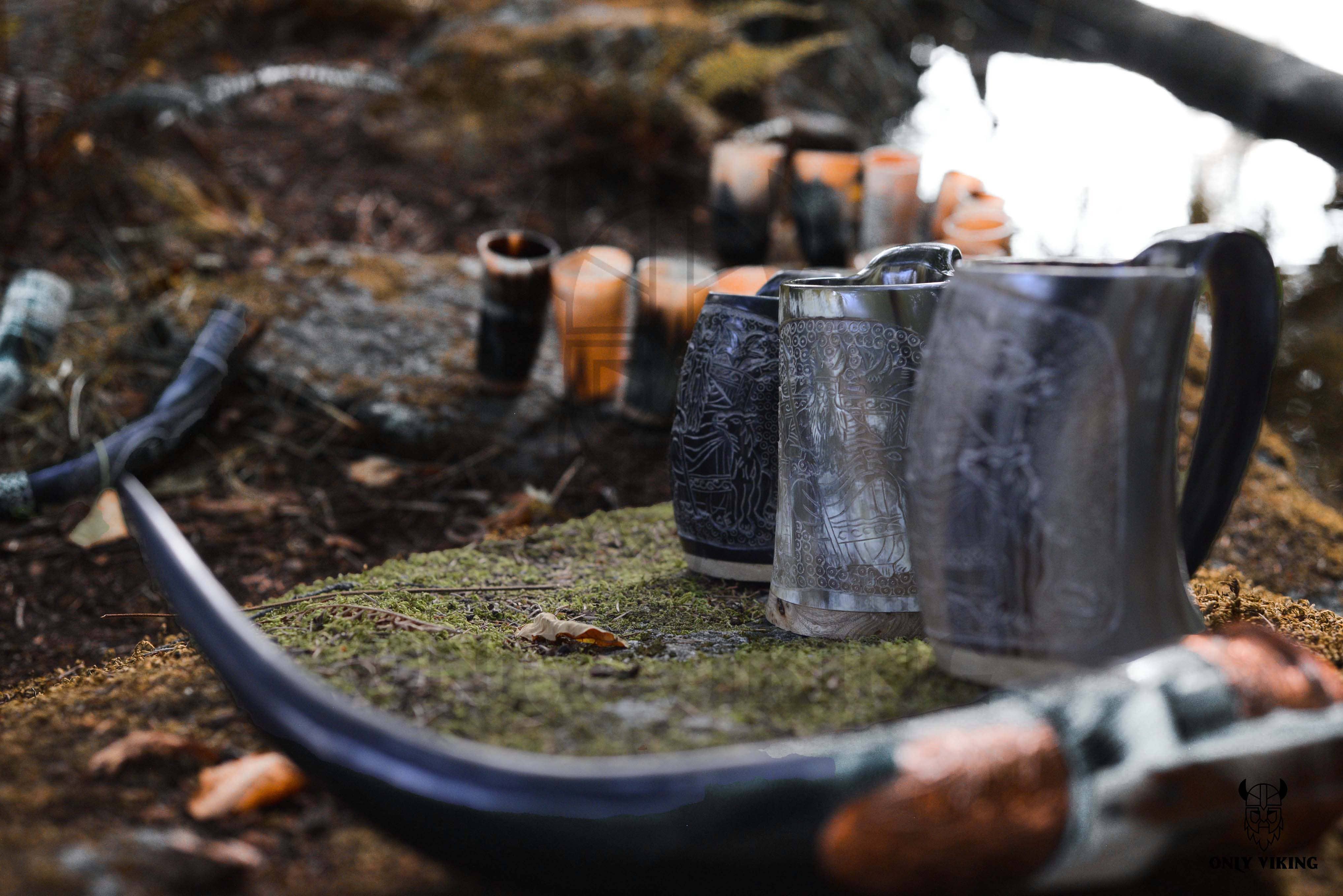 A Viking Tankard in white with black accents, ranging from 32 to 36 ounces, sits gracefully on a moss-covered surface among fallen leaves, with a softly focused backdrop capturing the spirit of an outdoor adventure.