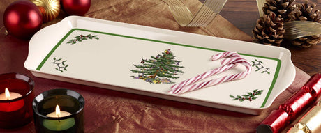 Rectangular melamine tray featuring a Christmas tree, candy canes, candles, ornaments, pinecones, and placed on a patterned holiday tablecloth.
