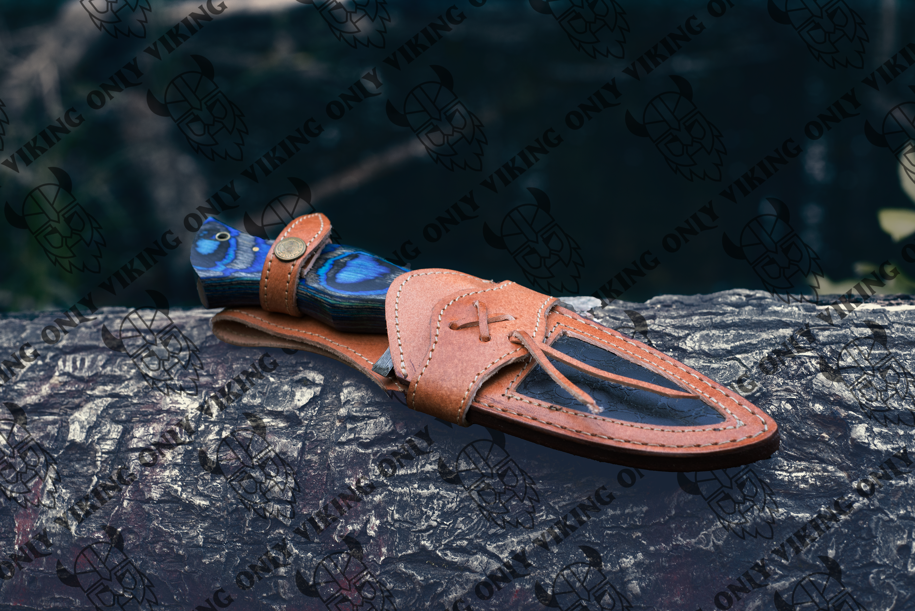 A handcrafted Damascus utility knife with a blue handle and leather sheath rests on a textured surface, showcasing its exclusive design with a Viking Only watermark.