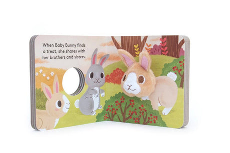 The "Baby Bunny Finger Puppet Book" is an interactive board book featuring illustrated bunnies in a grassy field and includes a soft bunny finger puppet for tactile play. Text: “When Baby Bunny finds a treat, she shares with her brothers and sisters.”.