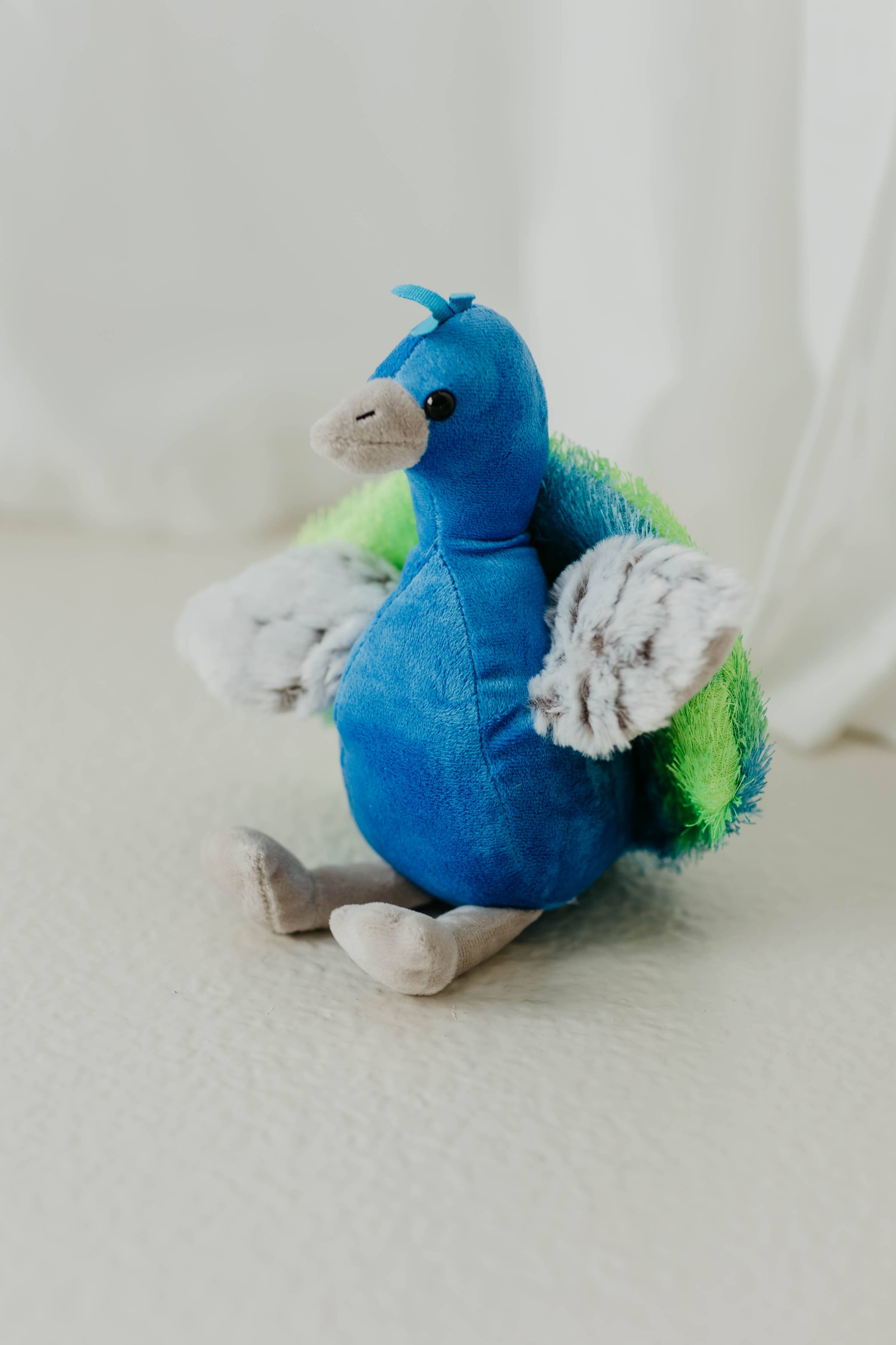 The Plush: Peacock Stuffed Animal 9 Tall Wild Onez features blue and green tail feathers, gray wings, beige feet, and is made from recycled water bottle fiber for an eco-friendly companion on any surface.