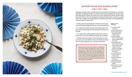A seafood salad, inspired by cozy Scandinavian recipes, is served on a blue-patterned plate surrounded by blue fans. Recipe is from "Scandinavian Gatherings" (paperback) by Melissa Bahen, published by Penguin Random House.