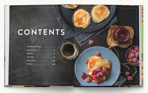 The open "Book: Beautiful Brunches" showcases a contents page on the left and an image of pancakes topped with berries and syrup on the right, accompanied by a small glass of dark liquid in the center, capturing the essence of this delightful cookbook.