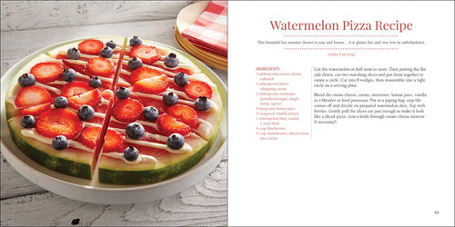 A watermelon slice topped with yogurt, strawberries, and blueberries is cut into pizza-style slices and displayed beside a page from the cookbook "Book: Strawberries 50 Tried & True Recipes.