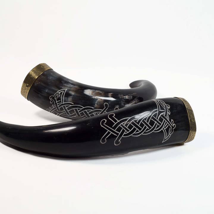 Two Viking drinking horns from the "Odin's Ravens" collection, featuring intricate silver engravings and metal bands, rest majestically on a plain white background.