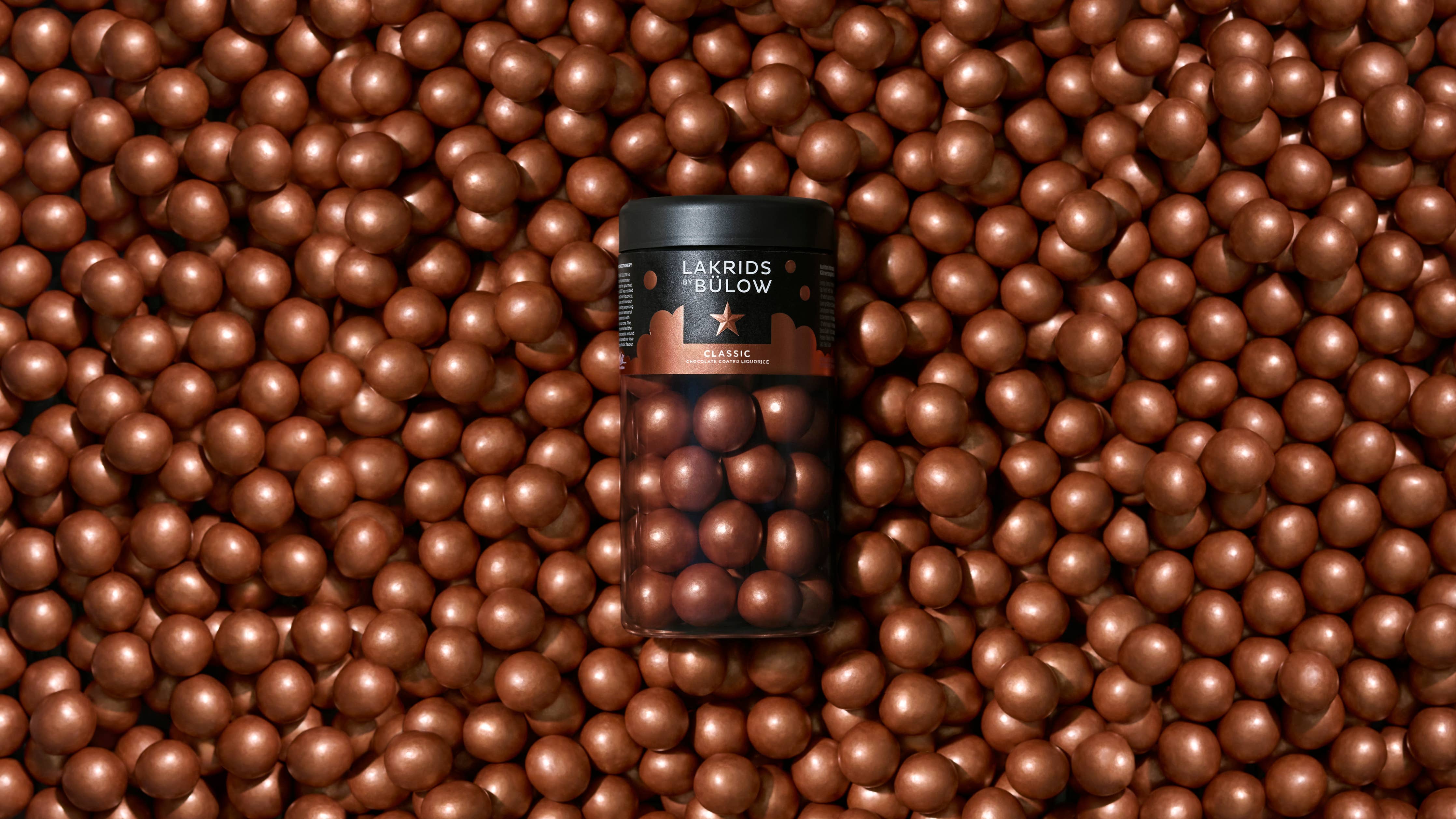 A jar of Candy:CLASSIC CARAMEL Chocolate Coated Licorice (Regular Limited Edition), surrounded by loose caramel chocolate licorice treats—ideal for those who crave a rich, gluten-free indulgence.