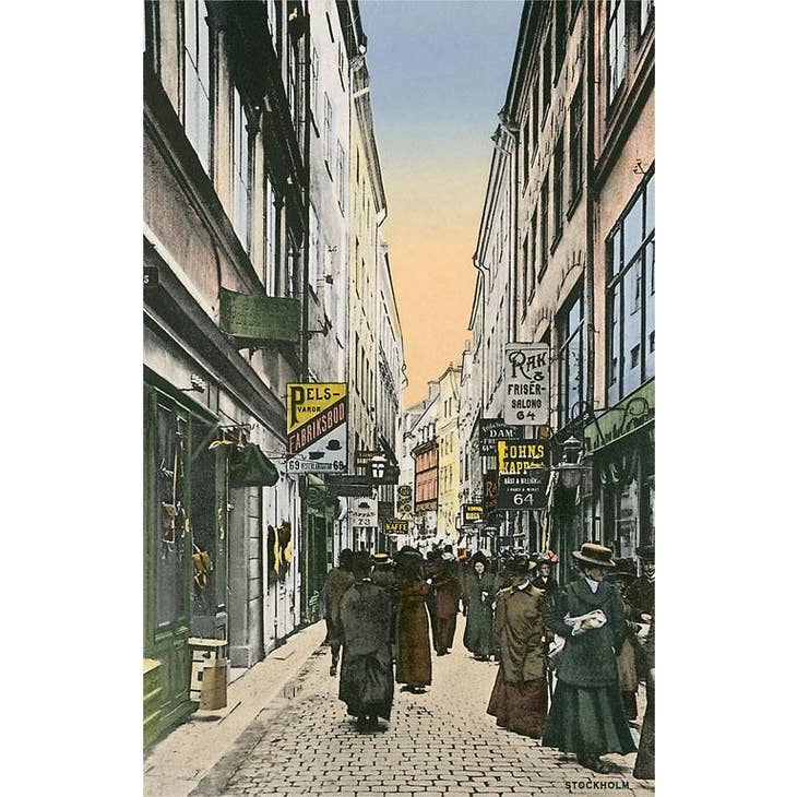 A bustling historical street scene comes to life much like the Post Card: Stockholm City Sidewalk, with people leisurely walking along a cobblestone path lined with tall buildings and delightful shop signs.