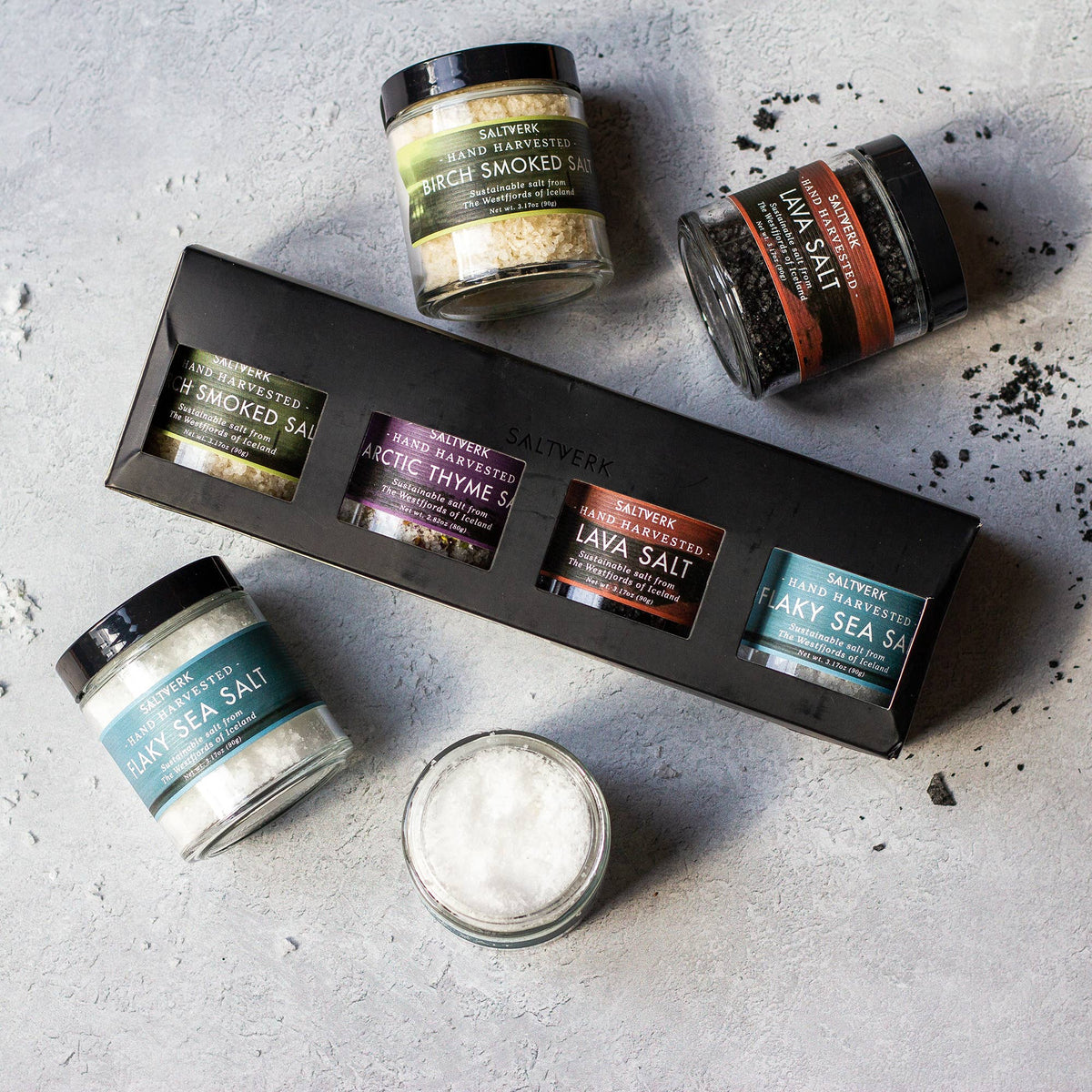 The SALTVERK Gift Set, featuring flaky sea salt, lava salt, birch smoked salt, and arctic thyme salt jars, is displayed on a light gray surface.