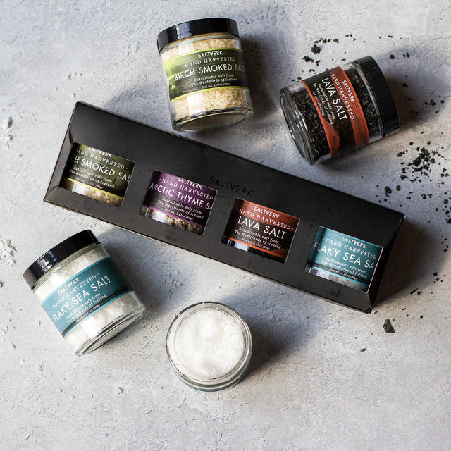 The SALTVERK Gift Set, featuring flaky sea salt, lava salt, birch smoked salt, and arctic thyme salt jars, is displayed on a light gray surface.
