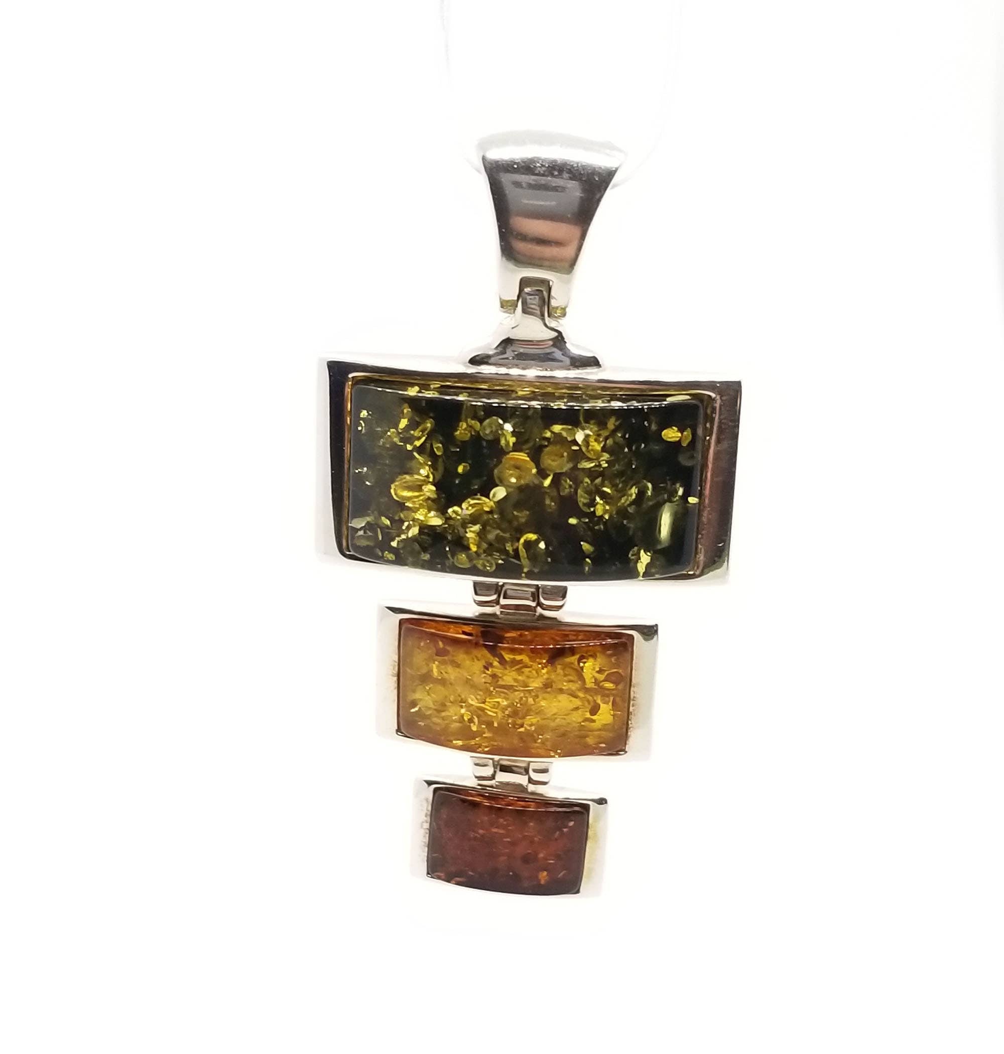 A pendant in sterling silver featuring genuine Baltic amber with three vertically connected rectangular stones, showcasing colors from dark green to light yellow to dark brown.