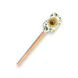 Spatula with a sunflower design and leaf pattern on the yellow silicone head, featuring a smooth wooden handle.