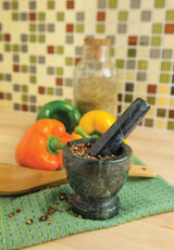 The Marble Mortar and Pestle, Green, 3.5"x3.5", sits on a green cloth with peppercorns, bell peppers, a wooden spoon, and a spice jar—ideal for grinding spices on your kitchen counter.