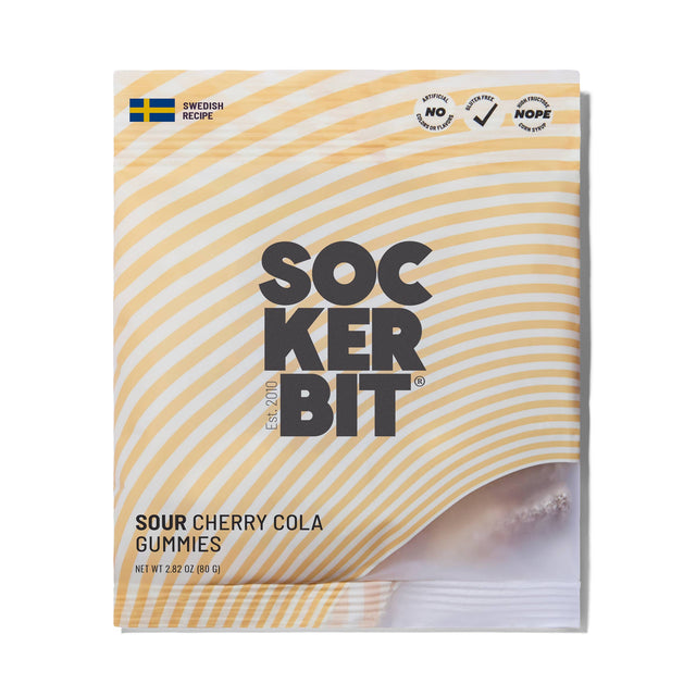 A bag of Sockerbit Sour Cherry Cola Swedish Candy features yellow diagonal stripes, bold black text, a Swedish flag icon, and some visible gluten free gummies. Net weight: 2.8oz (80g).