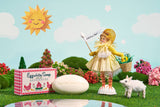 A whimsical scene with an Eggwhite & Rosewater Facial Soap 1.76oz box, oval soap bar, doll in a chick costume holding a flag, small lamb figure, and decorative trees under a sunny sky—perfect for radiant skin.