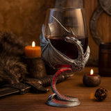 A glass of red wine fills the Wine Glass: Medieval Dragon Viking Goblet Mug (9oz) on a wooden table with candles, fur cloth, sword, and a 20-sided die—perfect for fans of Fantasy-Inspired Drinkware.