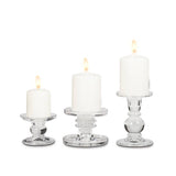 A white pillar candle burns atop the Small Reversible Candle Holder-3.5"L, adding a sophisticated touch to any setting.