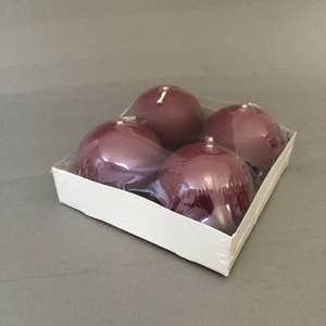 Four round Burgundy Ball Candles, each 2.5" in diameter, are wrapped in plastic and set in a white cardboard tray on a gray surface.