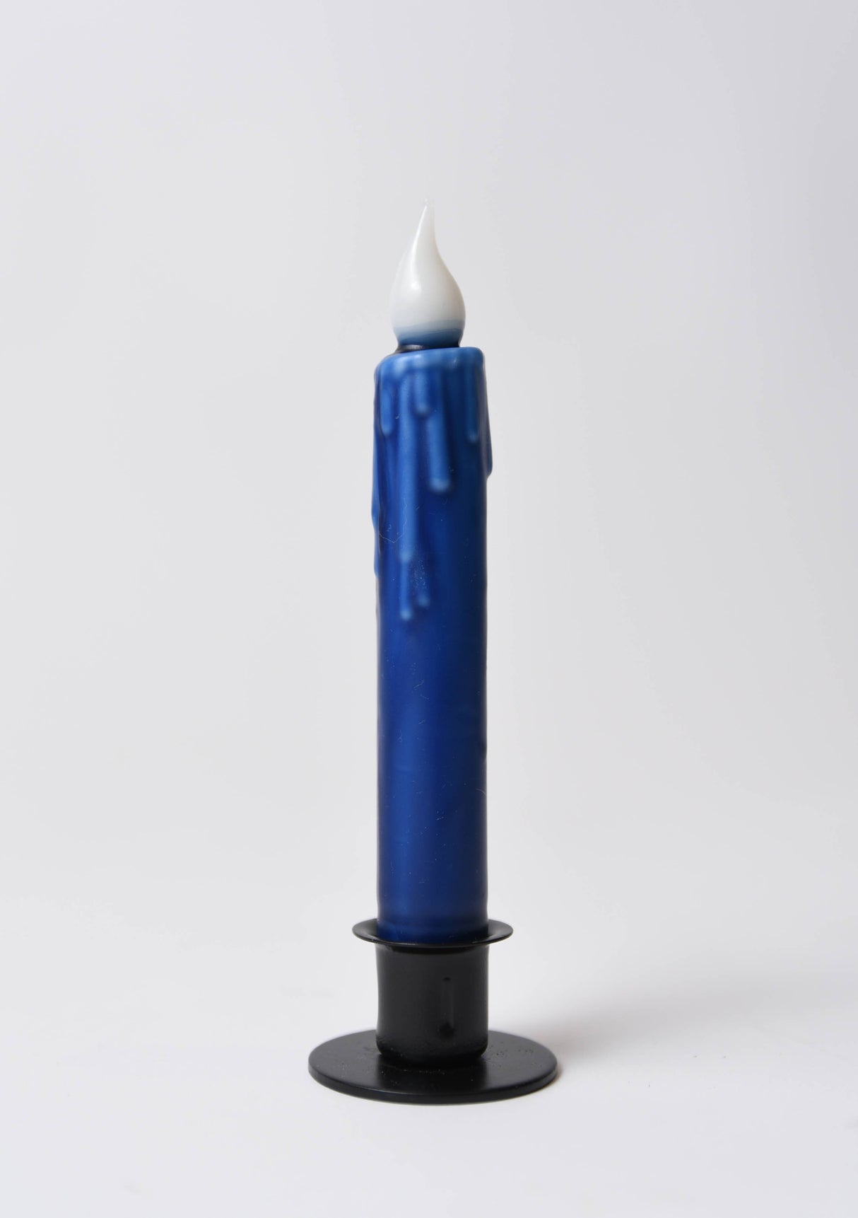A 7" Navy Blue LED Timer Taper Candle with a white flame-shaped top stands upright in a black holder against a plain white background.