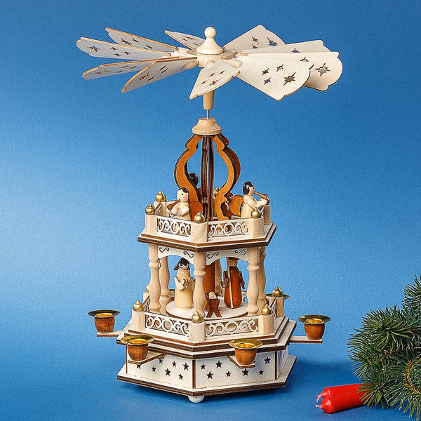 The Pyramid: Nativity 2 Tier Wooden Christmas Pyramid is handcrafted in Germany with rotating blades, a candle holder, and nativity figurines arranged on two tiers set against a blue background.
