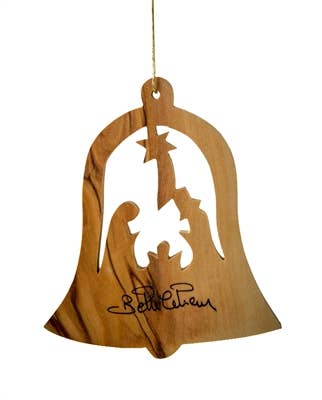 The 3" Bell with Nativity ornament is a handcrafted Bethlehem Christmas tree ornament featuring a cut-out nativity scene, a hanging string, and a black signature on the bottom.