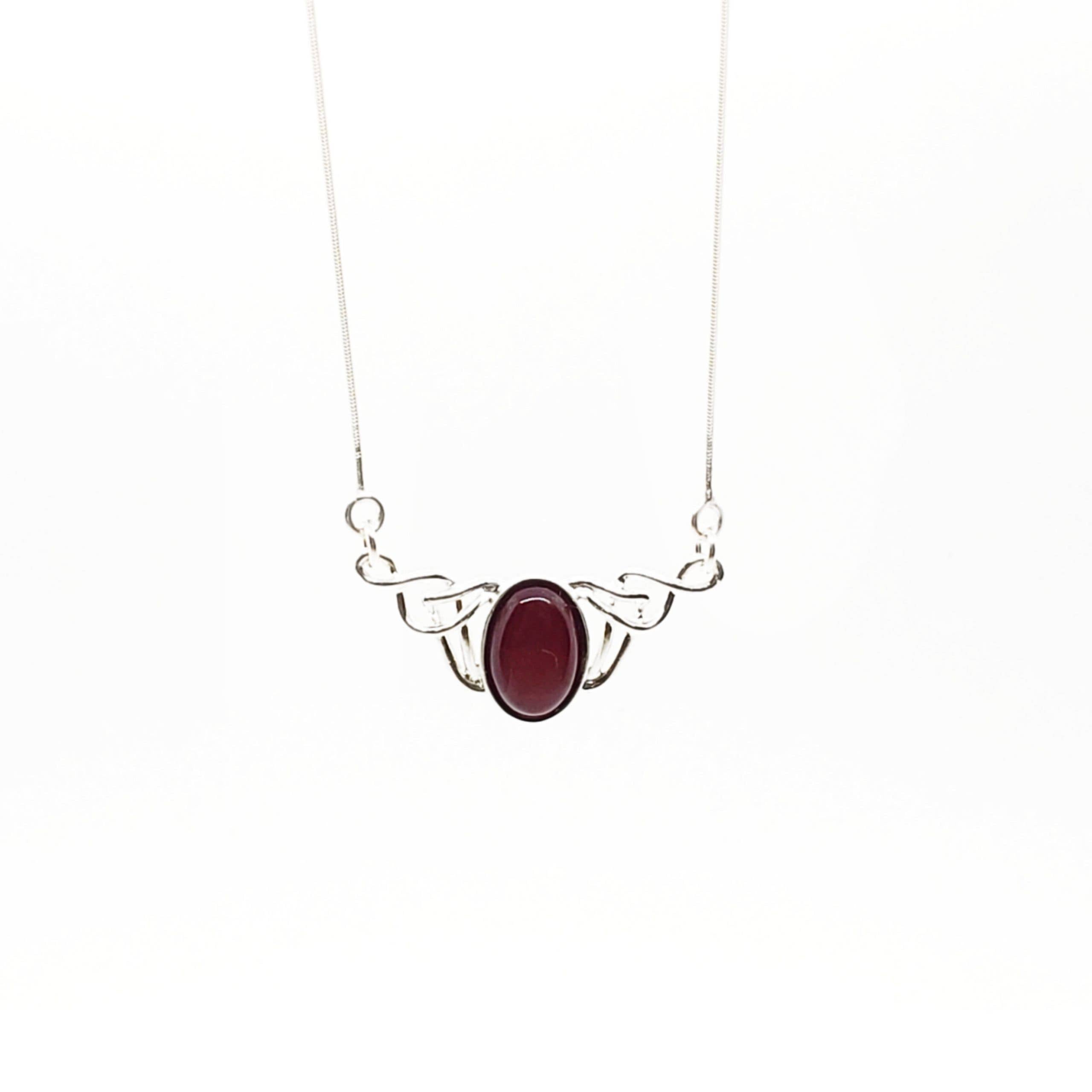 Cherry Amber Sterling Silver Necklace with a central oval red gemstone and decorative metalwork on either side, displayed on a plain white background. 17 chain.
