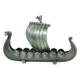 Celebrate Scandinavian heritage with the Figurine: Norwegian Viking Ship with Sail Pewter 5″x3″ Table Decor by Faire - Scandinavian Specialties. Expertly handcrafted, this metallic model features a striking dragon head at the prow, detailed round shields along the sides, and a classic sail—beautifully presented against a plain white background and capturing the spirit of Norway’s iconic longships.