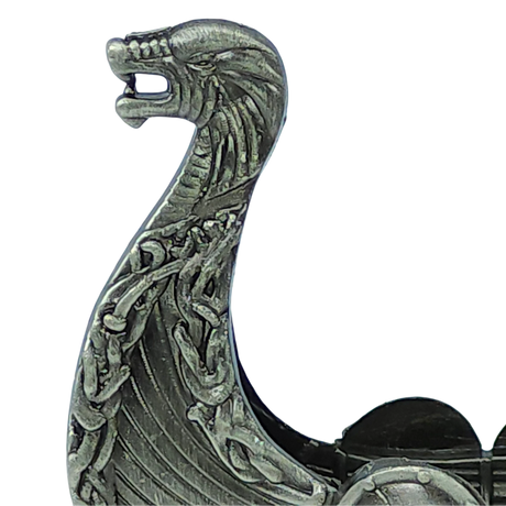 A close-up of the “Norwegian Viking Ship with Sail Pewter 5′‘x3’’ Table Decor” by Faire - Scandinavian Specialties, showcasing the figurine’s intricately detailed metallic dragon head prow adorned with knotwork patterns inspired by traditional Norwegian craftsmanship.